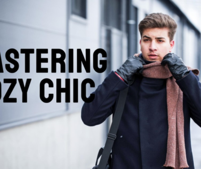 A person with their face obscured by a pixelated block stands outside near a building, wearing a winter coat and scarf, with the phrase “MASTERING COZY CHIC” overlaid in large white letters.